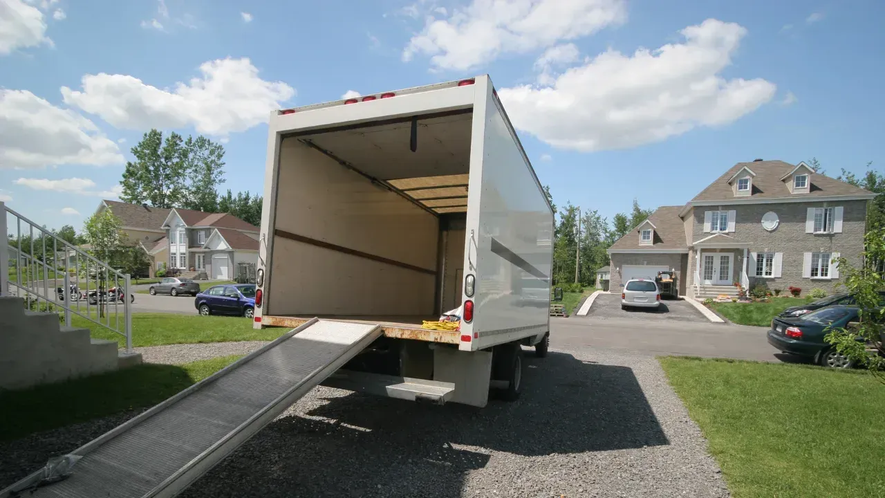 a moving truck parked in a home's driveway with a ramp down