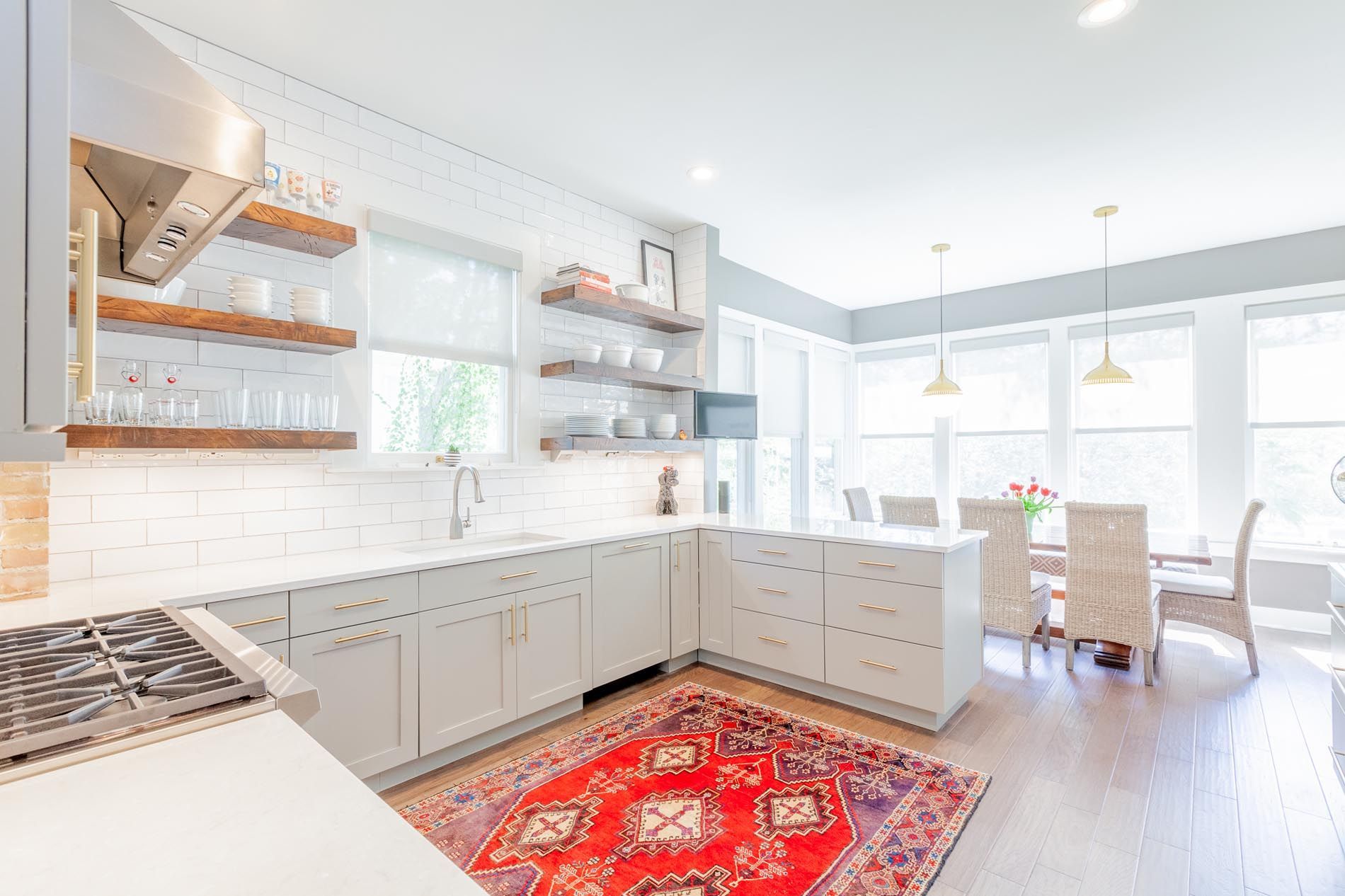 A kitchen with white cabinets and a red rug on the floor.