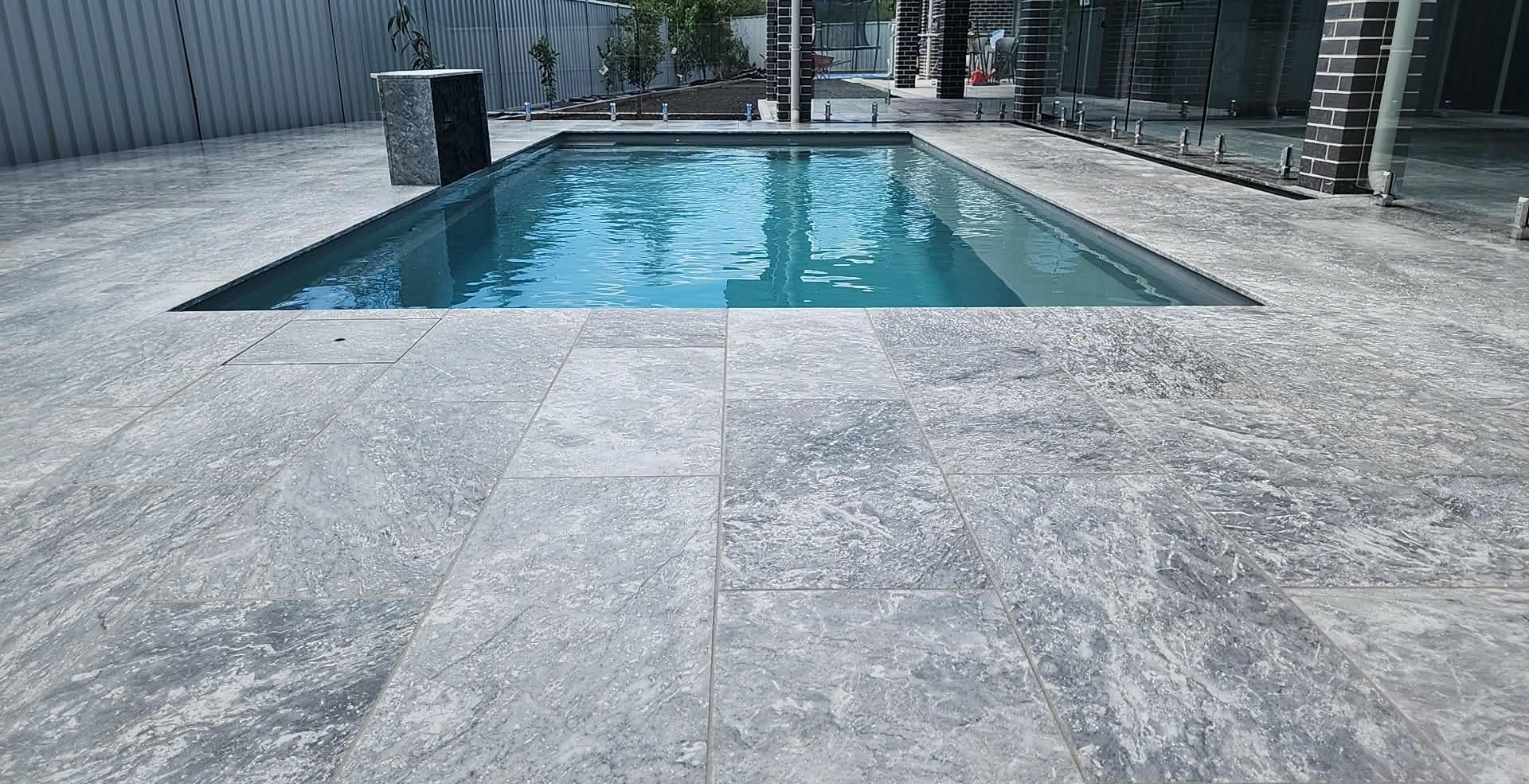 Rectangular pool with blue water, surrounded by light grey stone tiles, in a backyard setting. — Clearwater Pools Hallidays Point In Hallidays Point, NSW
