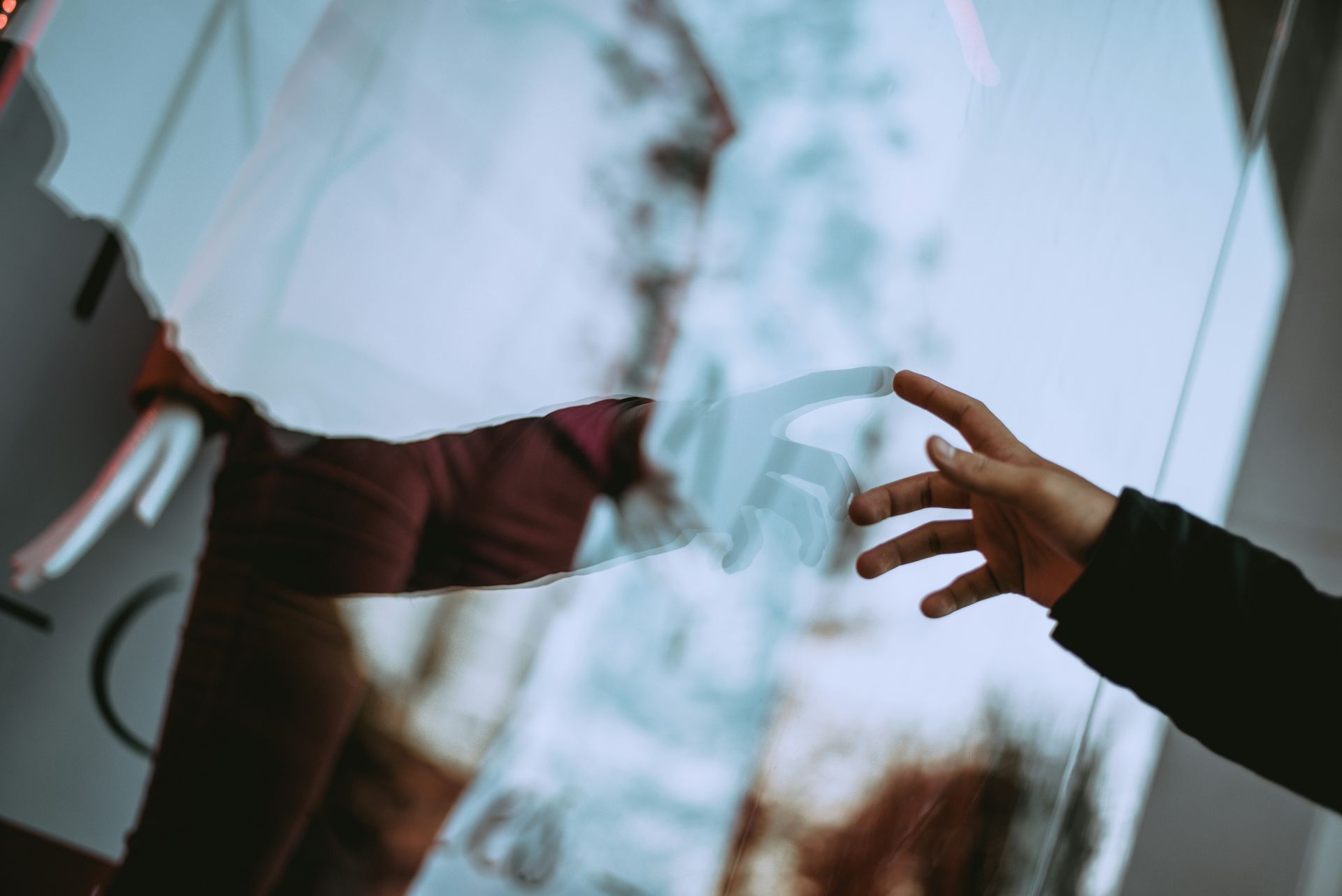 A person is touching a mirror with their hand.