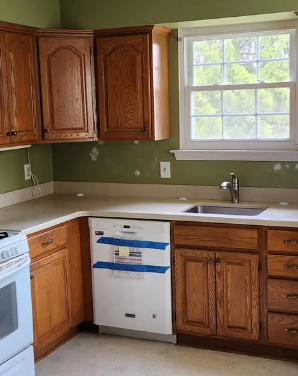 Kitchen with wood cabinets, light countertops, and a dishwasher under a window.