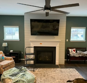 Living room with dark green walls, a fireplace, and a large TV above it.