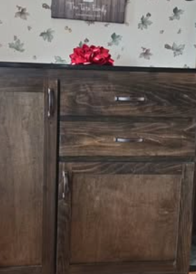 Wooden cabinet with dark stain, silver hardware, and a red bow on top.