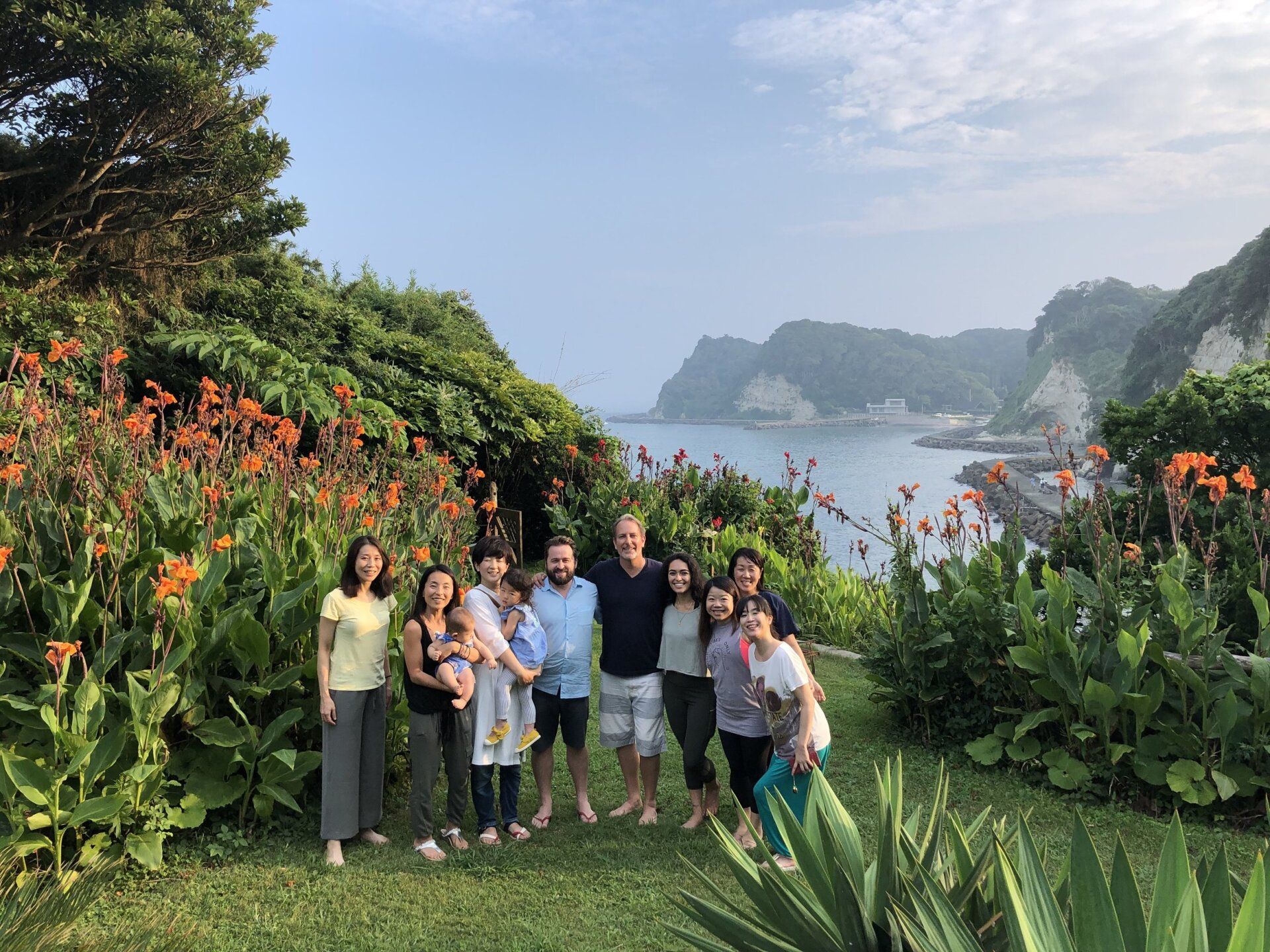 A group of people are posing for a picture in front of a body of water.
