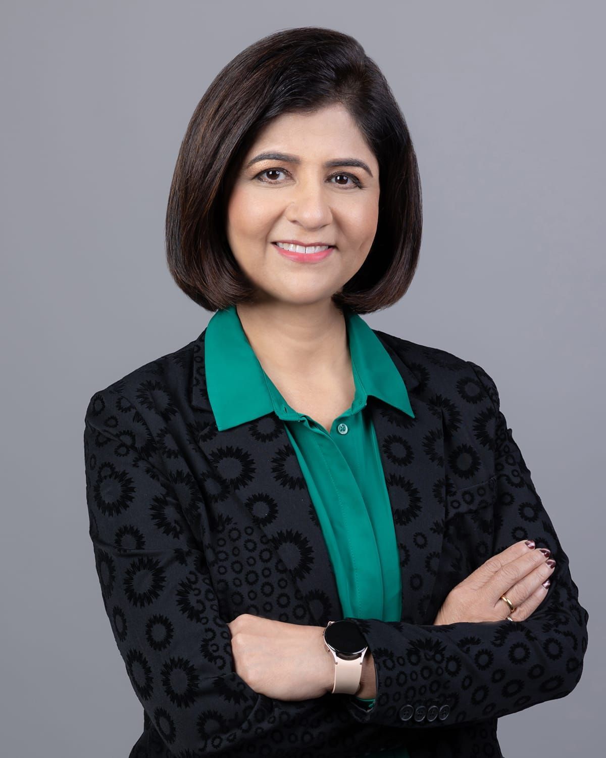 A woman wearing a black jacket and a green shirt with her arms crossed