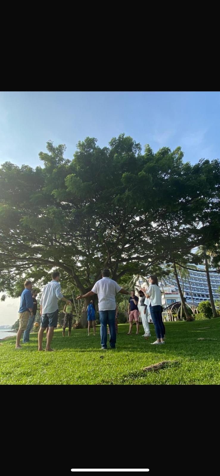 A group of people are standing around a tree in a park.