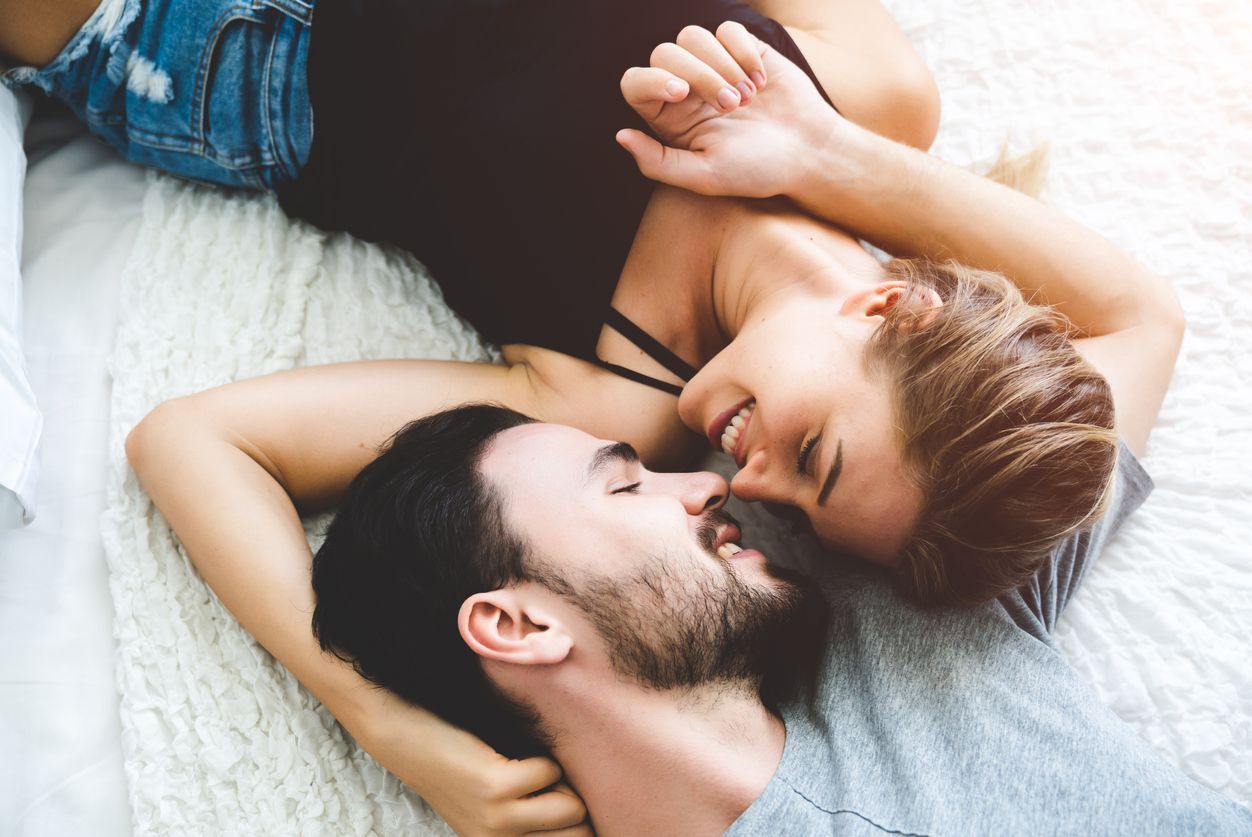 A man and a woman are laying on a bed.