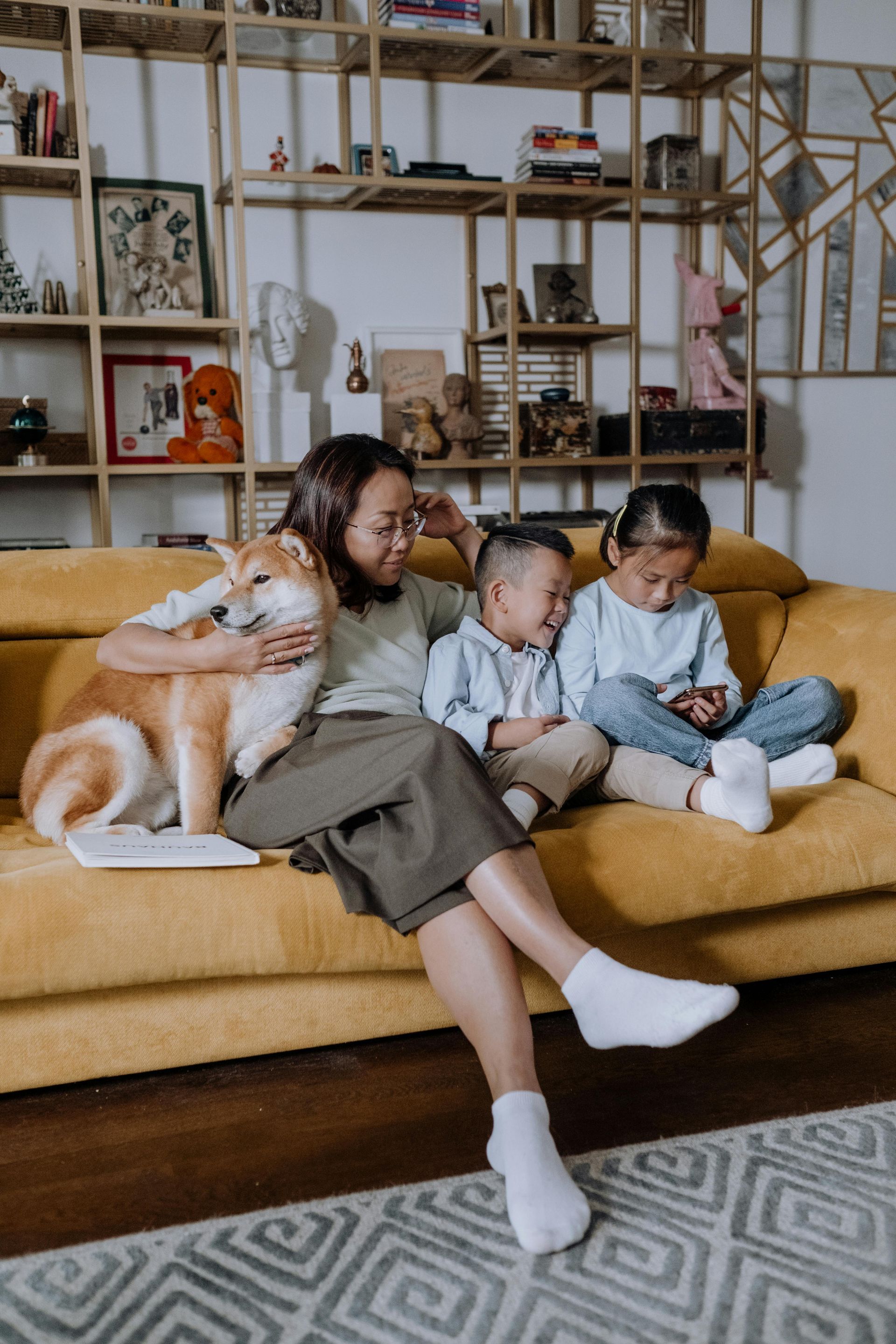 A woman is sitting on a couch with two children and a dog.