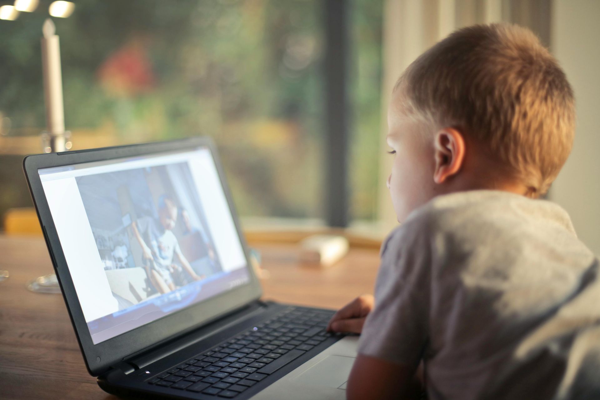 A young boy is sitting at a table using a laptop computer.