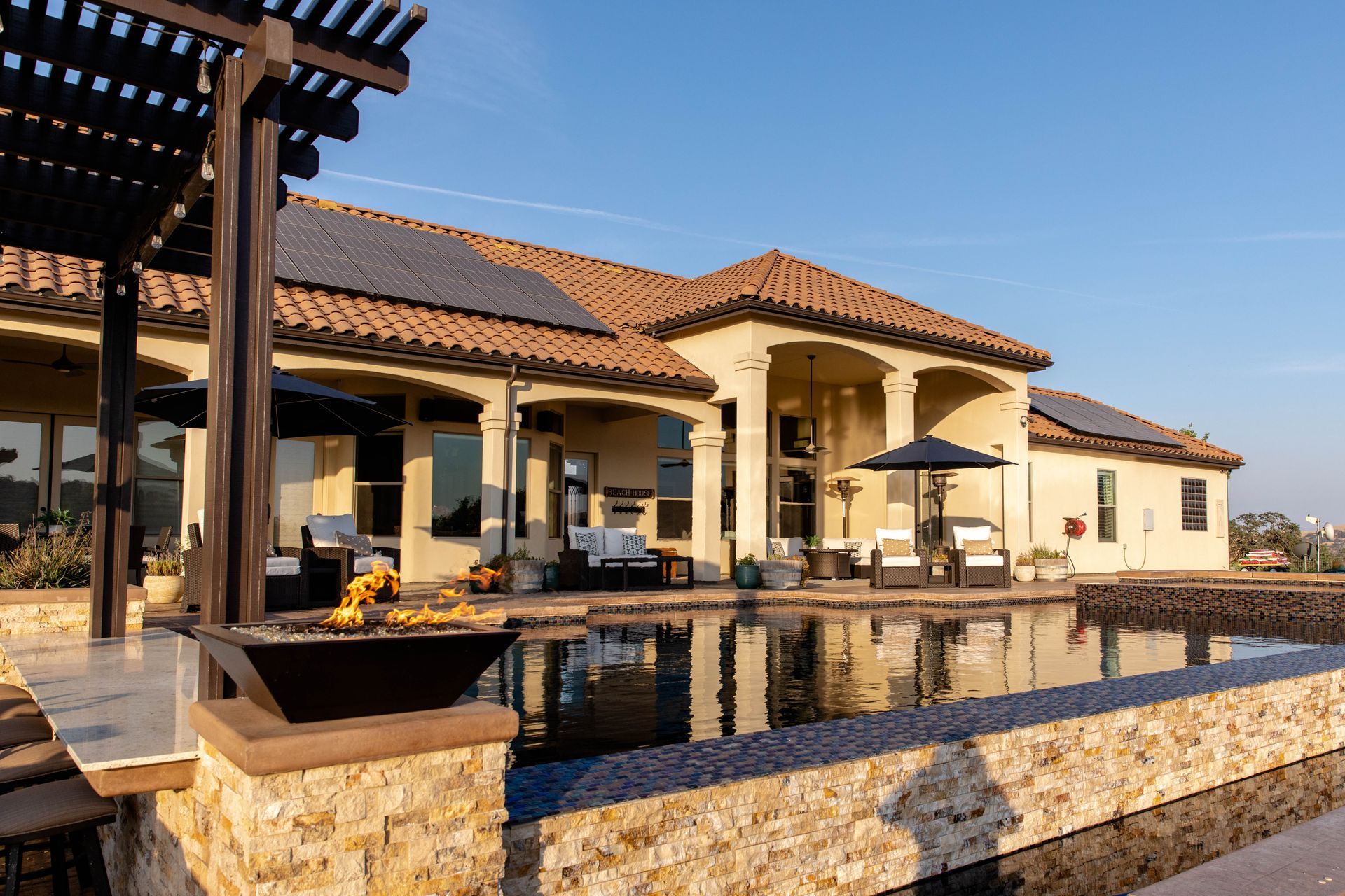 Luxury villa with terracotta roof, pool, and stone patio under a clear blue sky