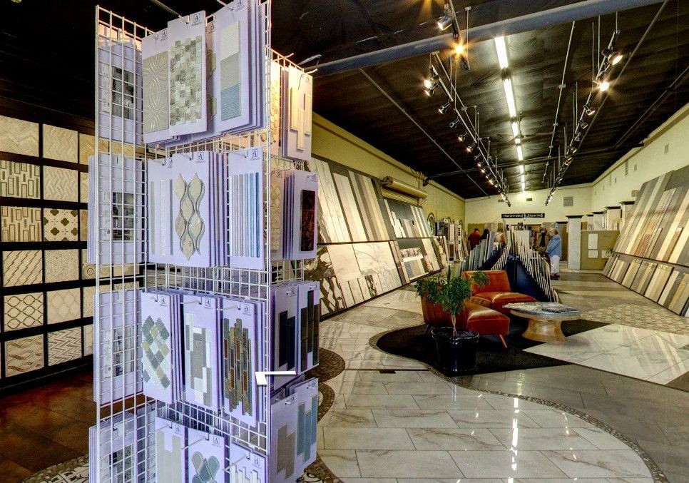 Interior of a tile showroom with displays, patterned tiles, and red seating under bright ceiling lights