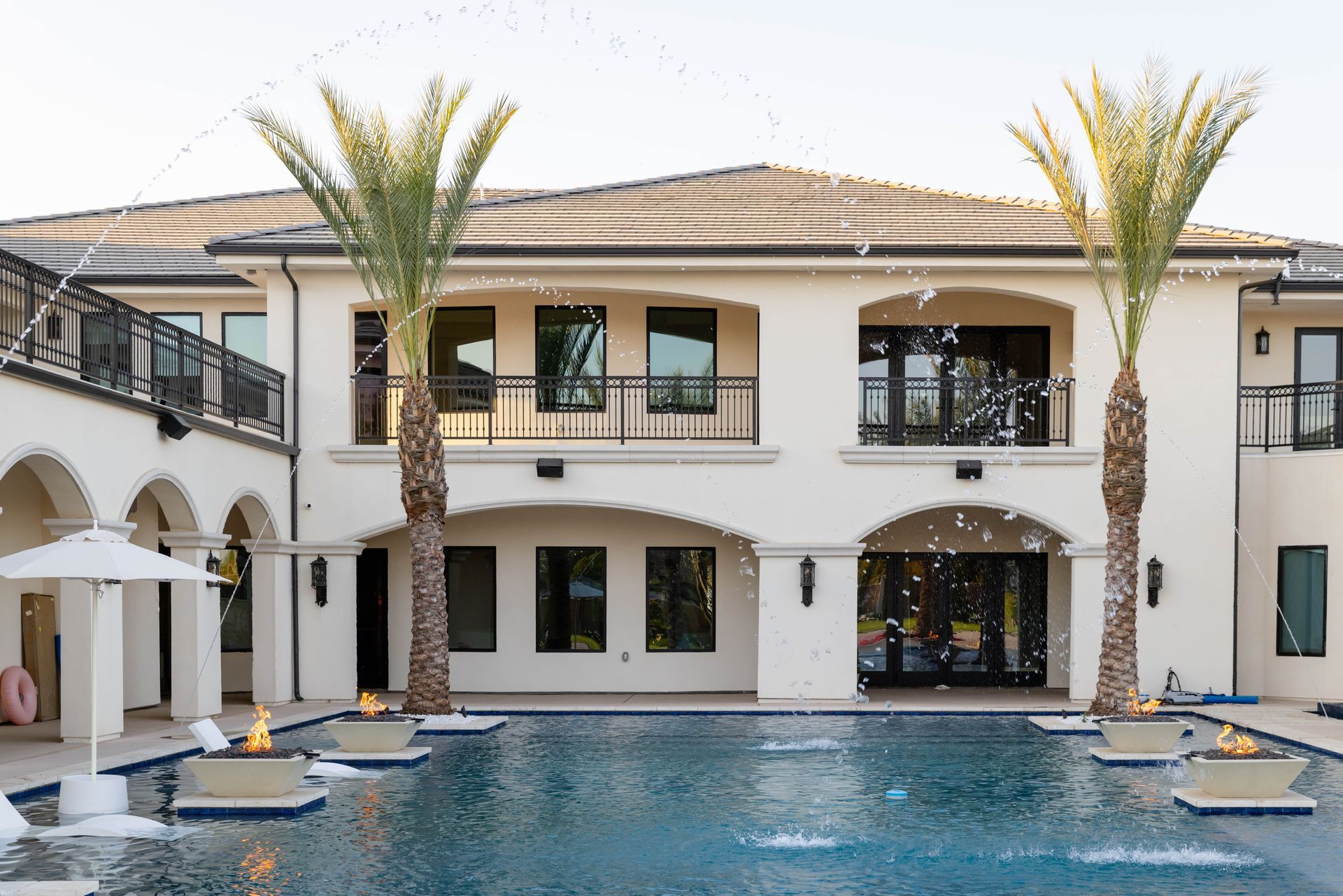 Luxury villa with palm trees and a blue swimming pool at the front patio