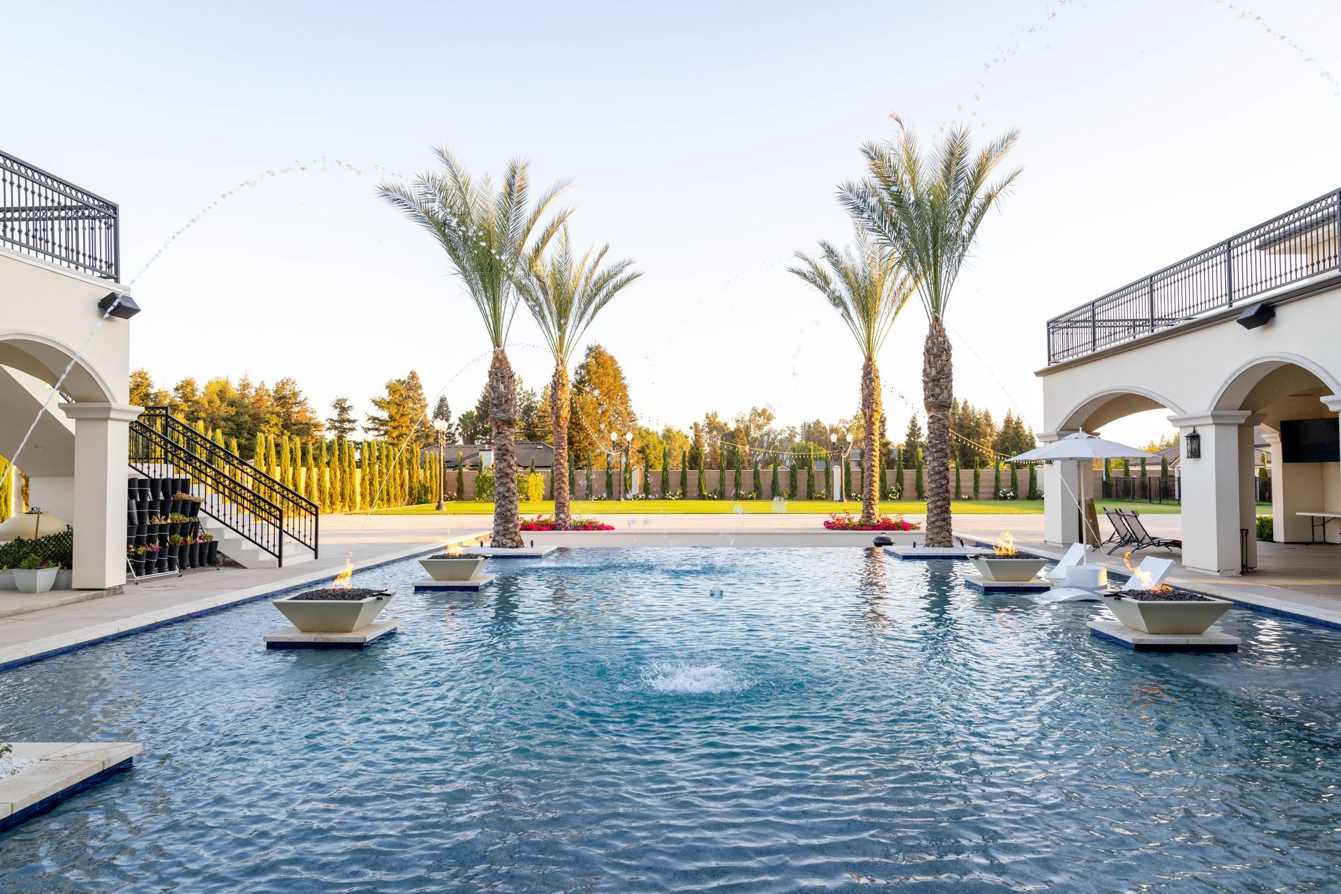 Luxury outdoor pool with palm trees and white buildings, reflecting water under a bright sky