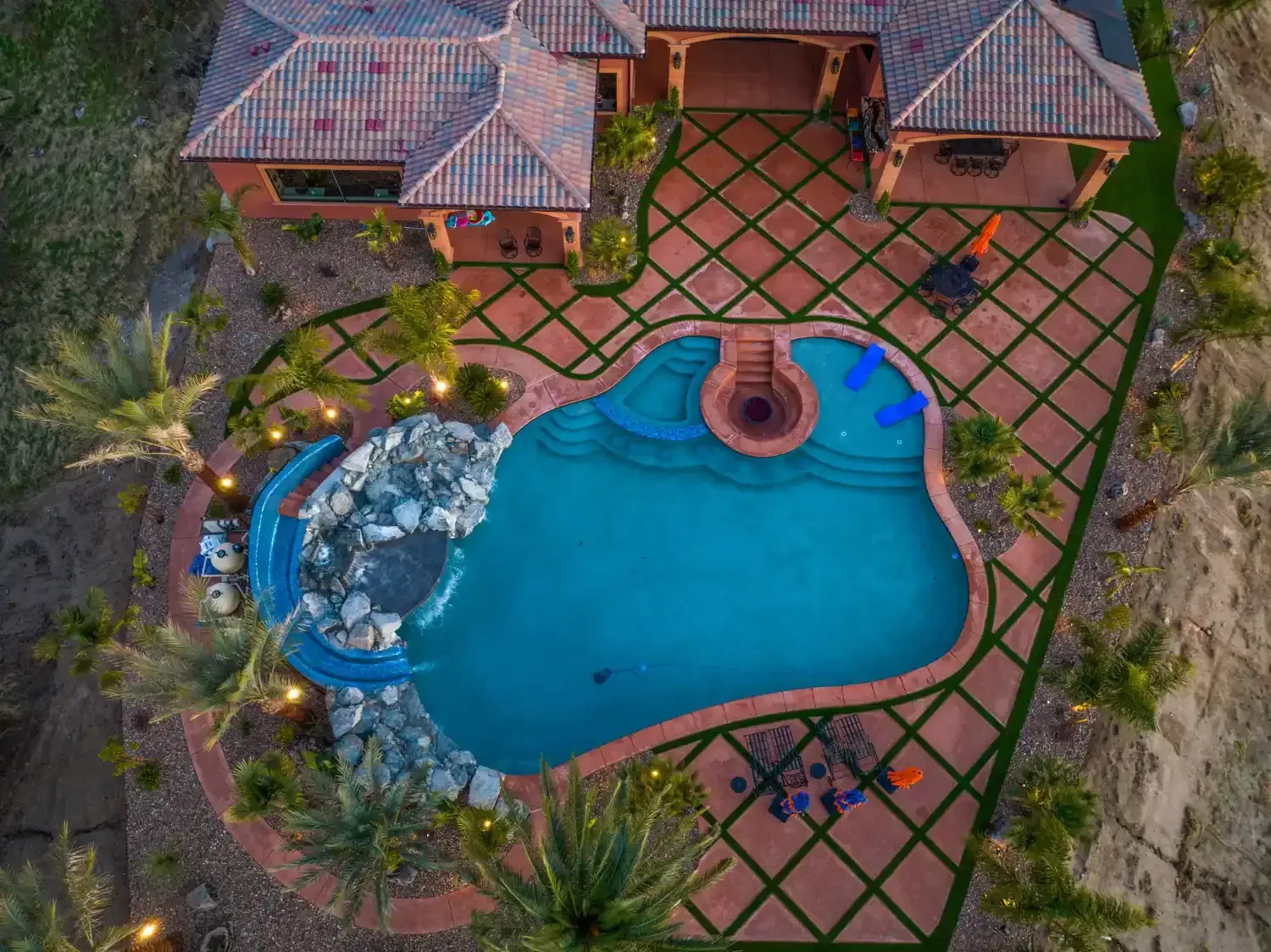 Aerial view of a backyard pool with patio, lounge chairs, and surrounding landscaping.
