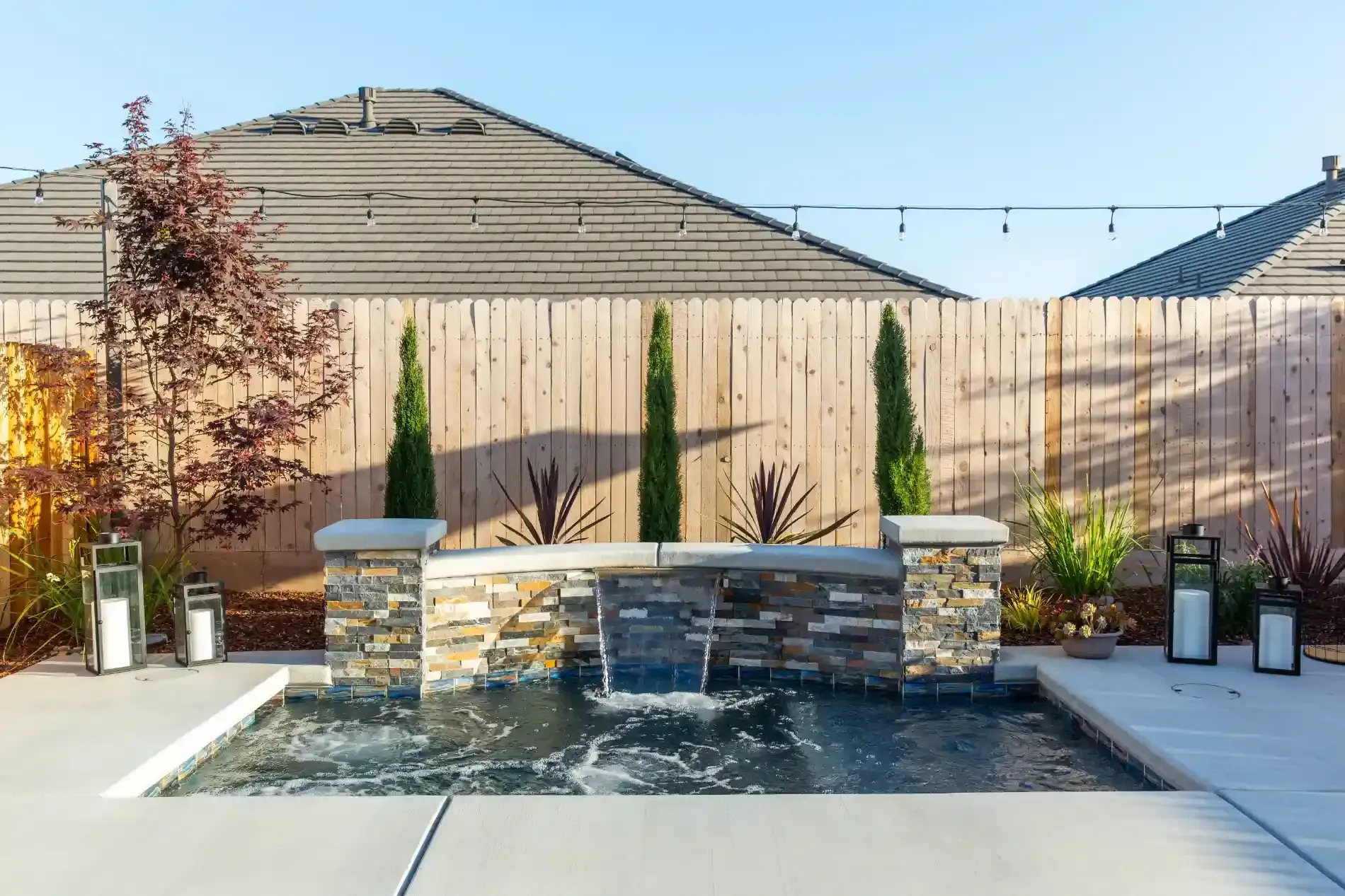Backyard patio with a stone fire pit and built-in bench seating against a wooden fence