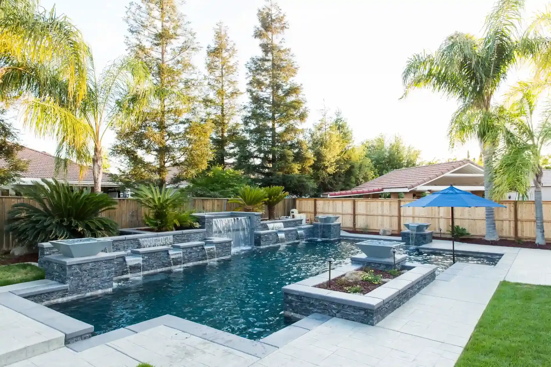Backyard pool with waterfall, fire feature, palm trees, and lounge area