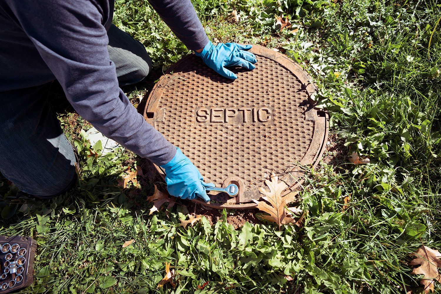 Plumber opening a septic tank for inspection and maintenance.