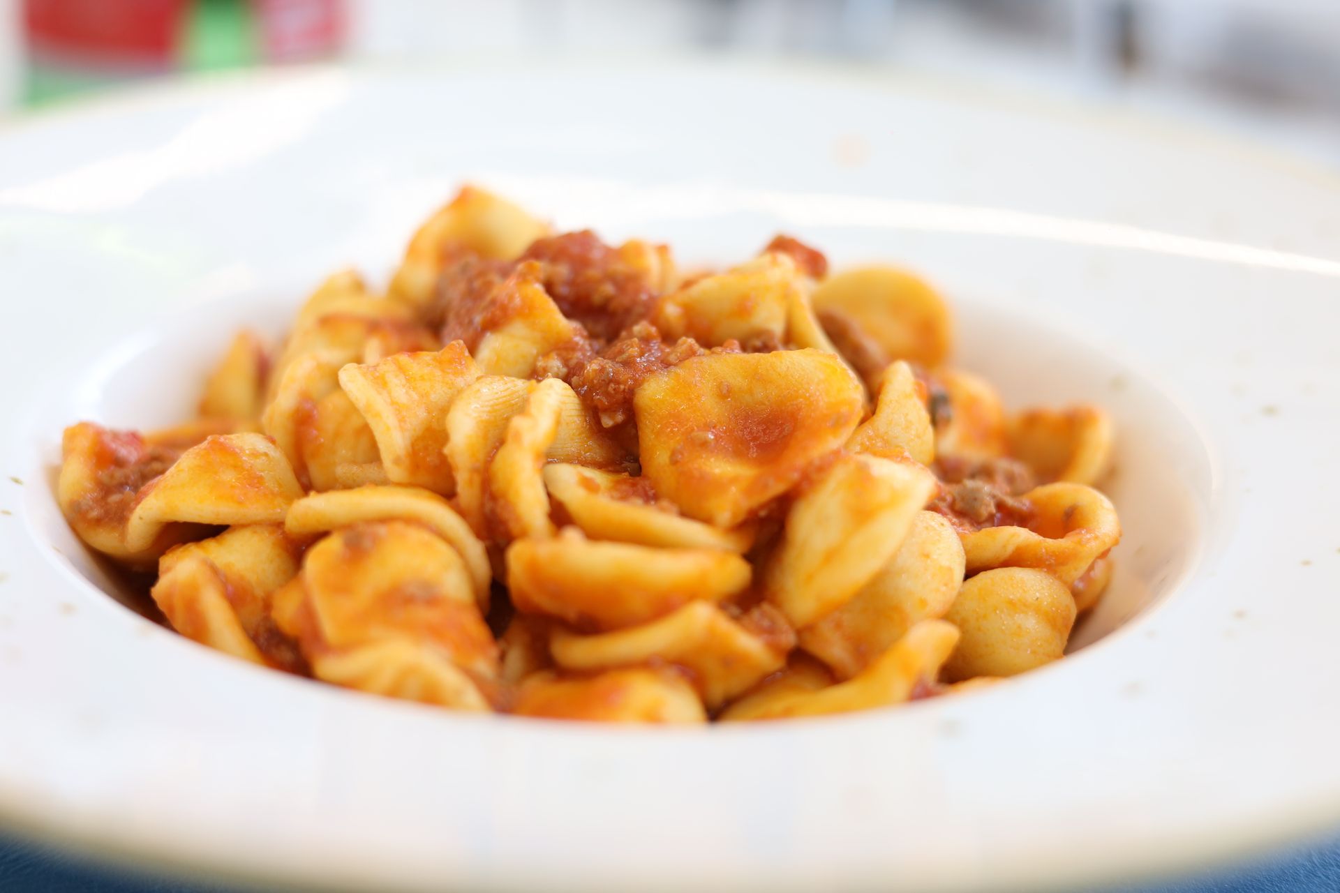 Orecchiette con sugo di pomodoro e carne in una ciotola bianca.