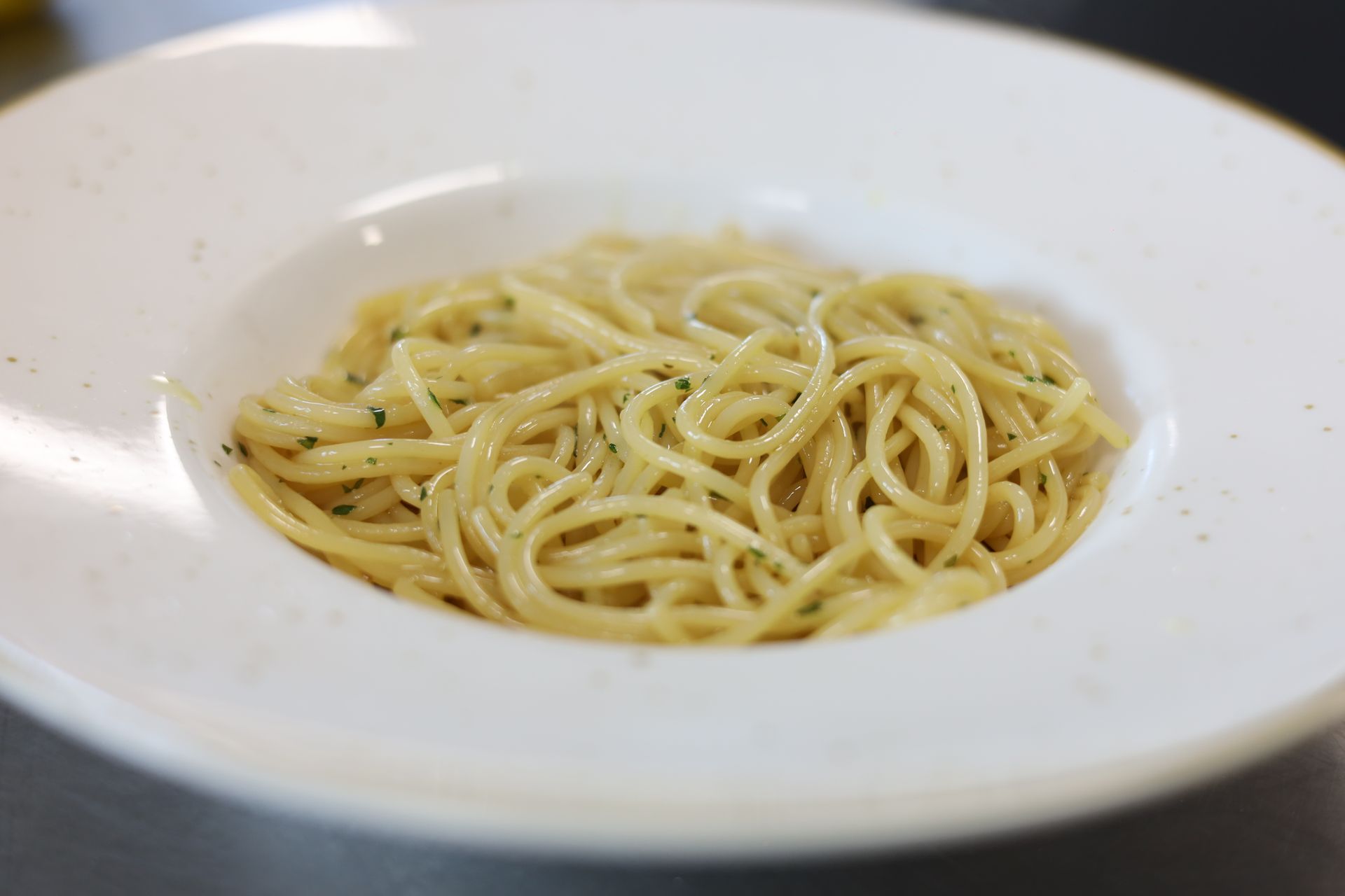 Pasta orecchiette e salsa verde mescolate in una padella sul fornello con un cucchiaio di legno.