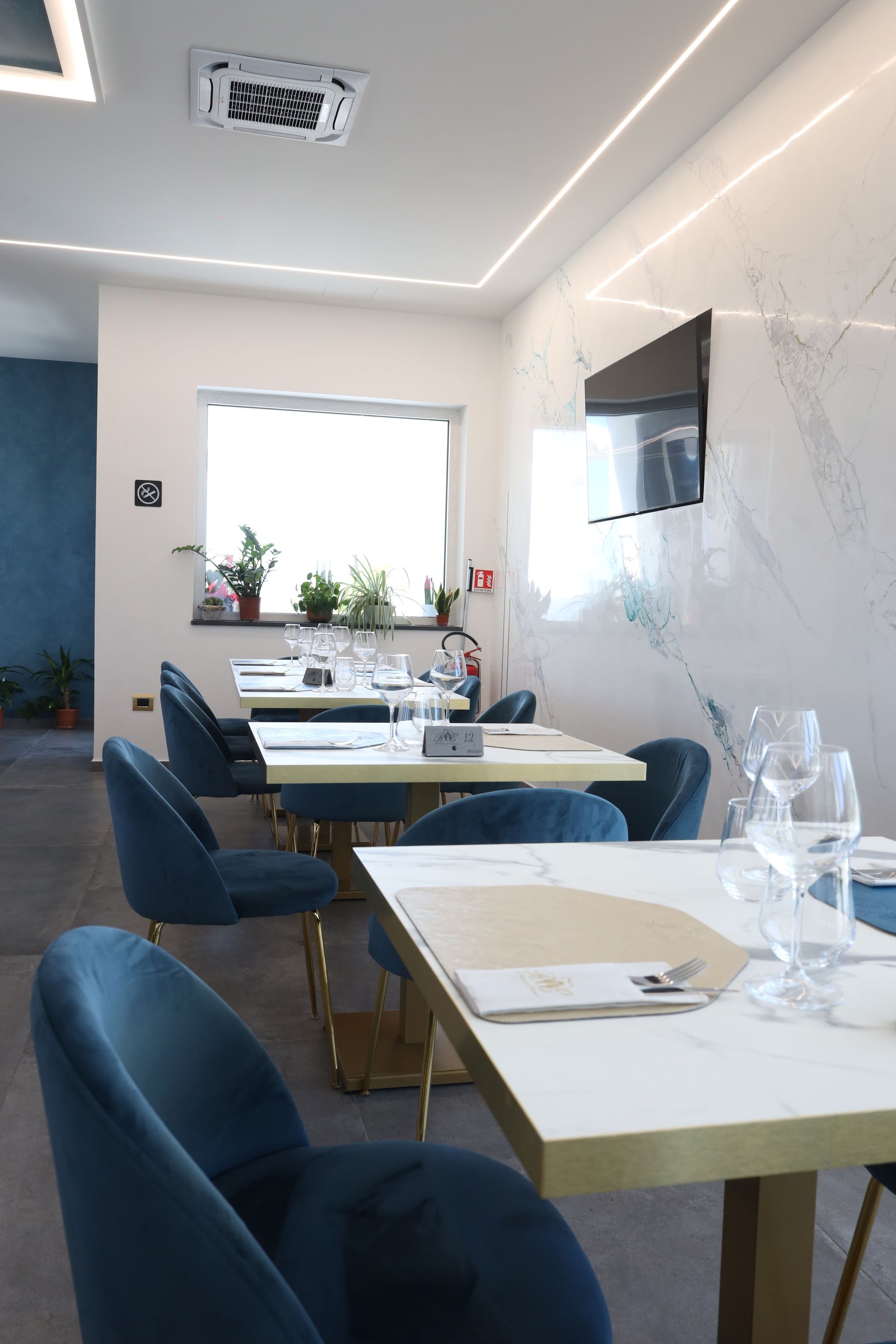 Patio esterno con tavoli e posti a sedere, con vista su un paesaggio con turbine eoliche sotto un cielo azzurro brillante.