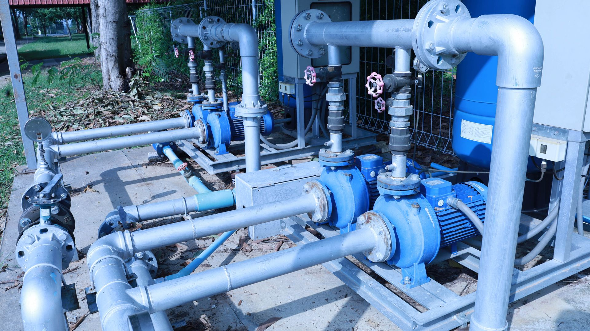 Blue water pumps and piping in an outdoor setting.