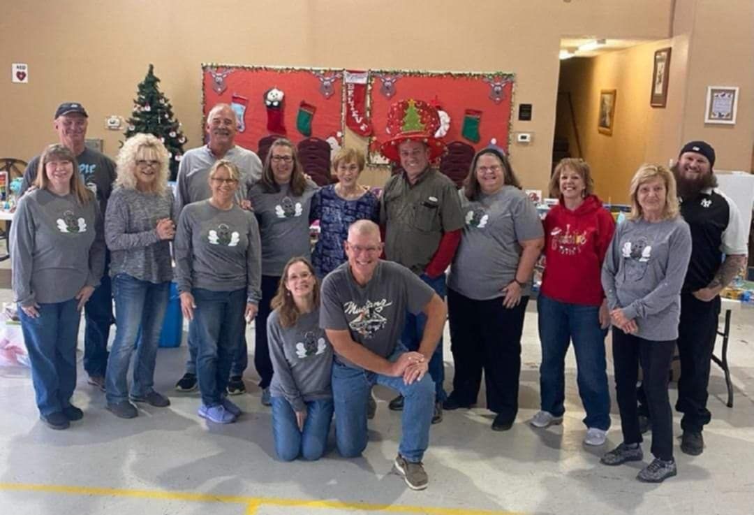 A group of people are posing for a picture in front of a christmas tree.