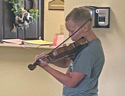 A young boy is playing a violin in a room.