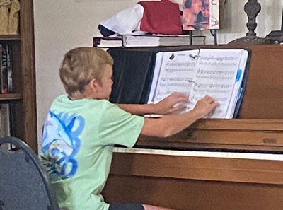 A young boy in a green shirt is playing a piano.