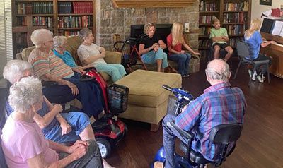 A group of elderly people are sitting in a living room.