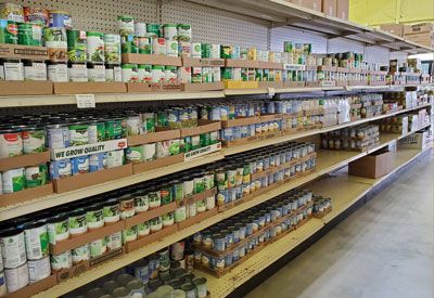 Shelves of canned goods in a grocery store, variety of sizes and brands, neatly organized.