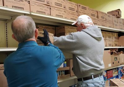 Two men are working on a shelf in a store.