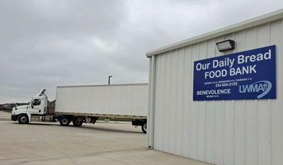 A truck is parked in front of a building that says our daily bread food bank.