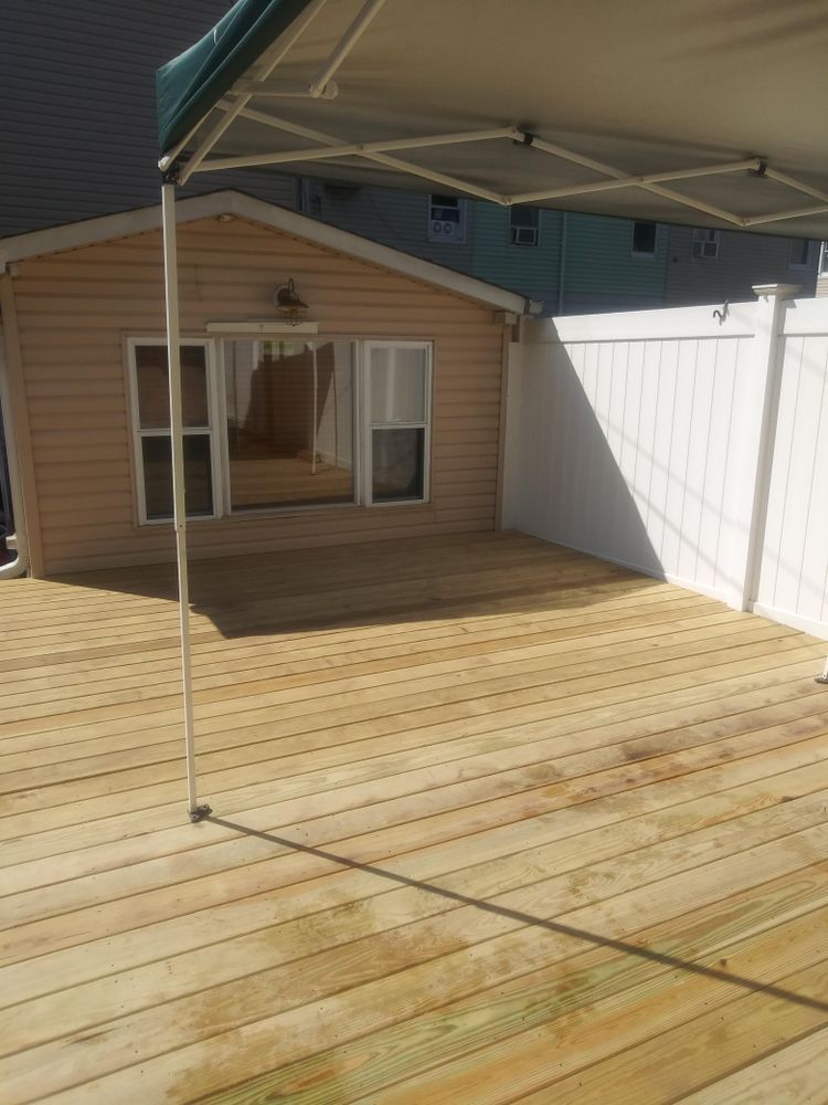 A wooden deck with a canopy over it in front of a house