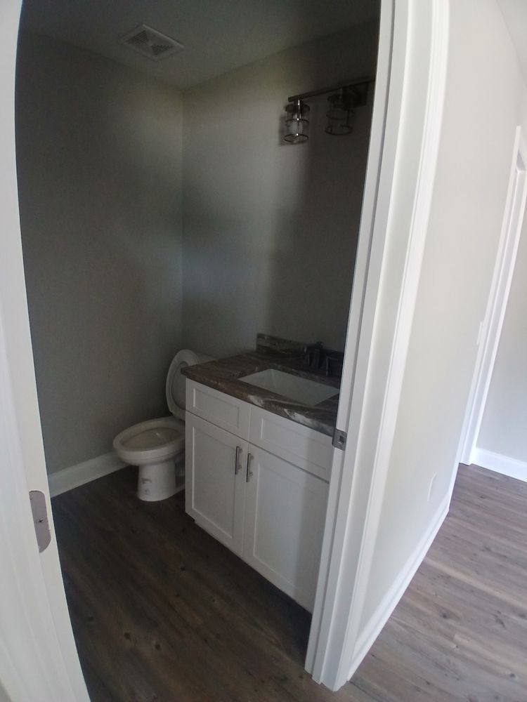 A bathroom with a toilet, sink and cabinets