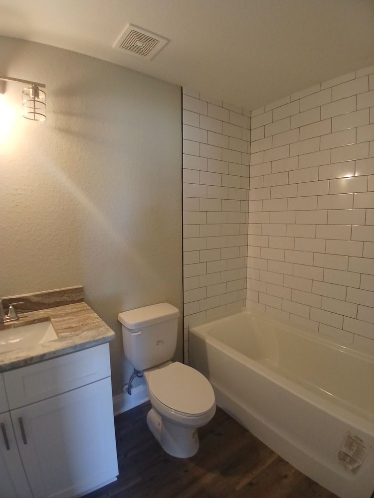 A bathroom with a toilet , sink and bathtub.