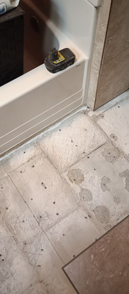 A bathroom floor with a bathtub in the background
