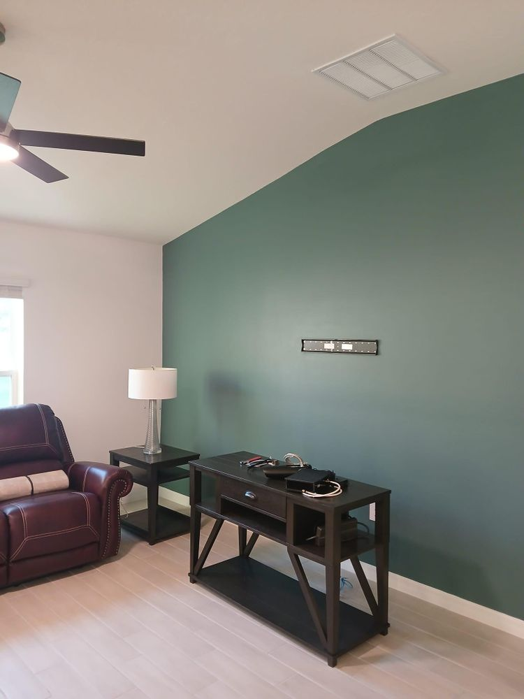 A living room with green walls and a ceiling fan
