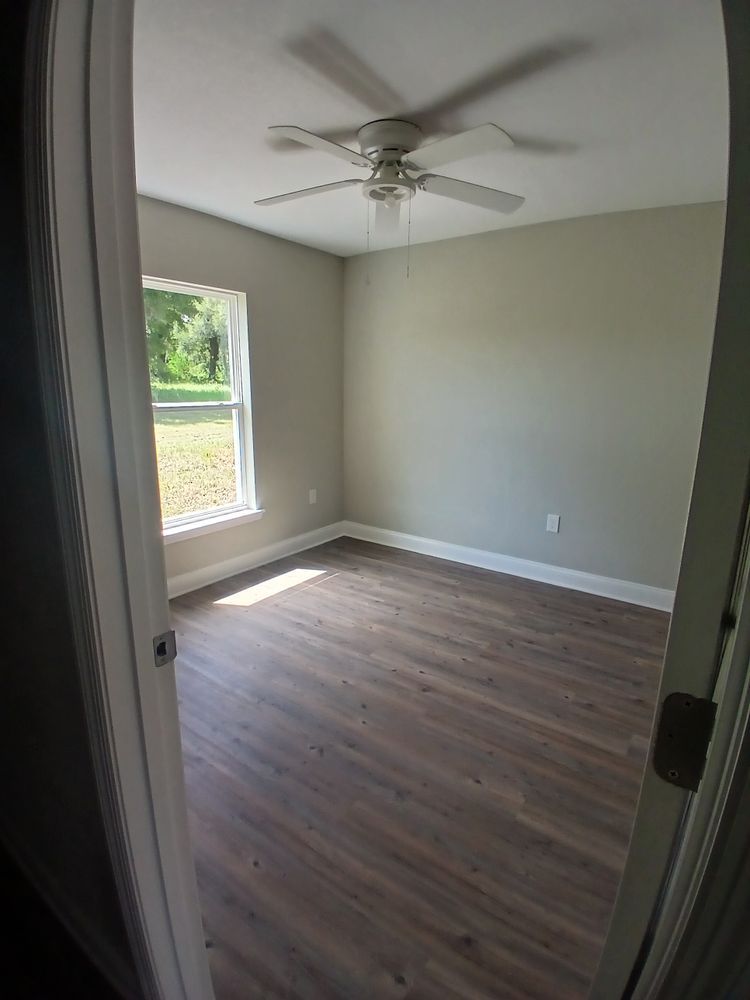 An empty bedroom with a ceiling fan and a window