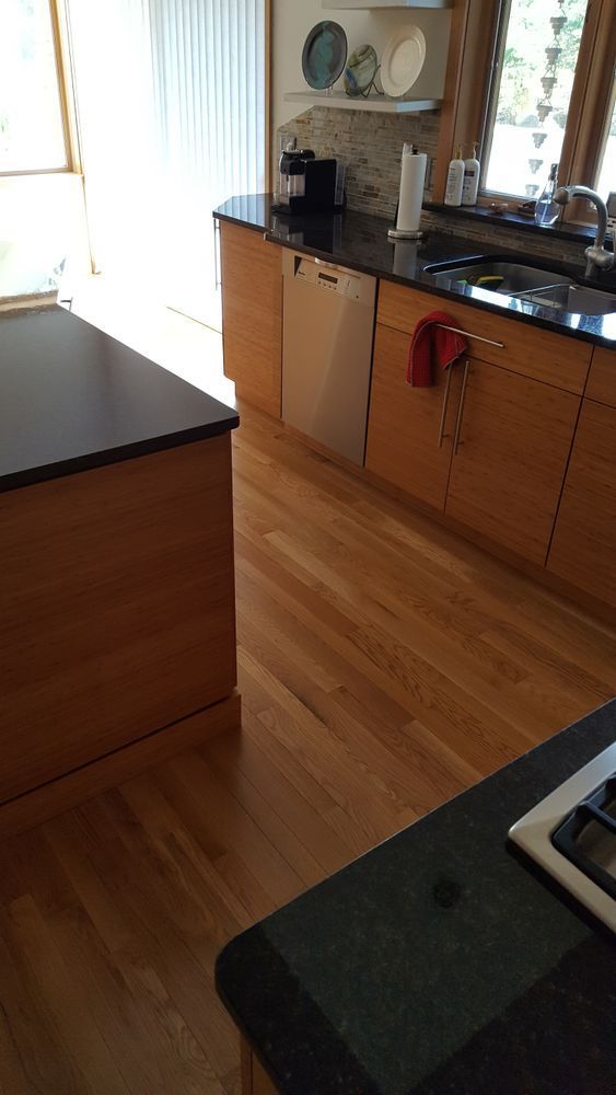 A kitchen with wooden cabinets, black counter tops, a sink, and a dishwasher