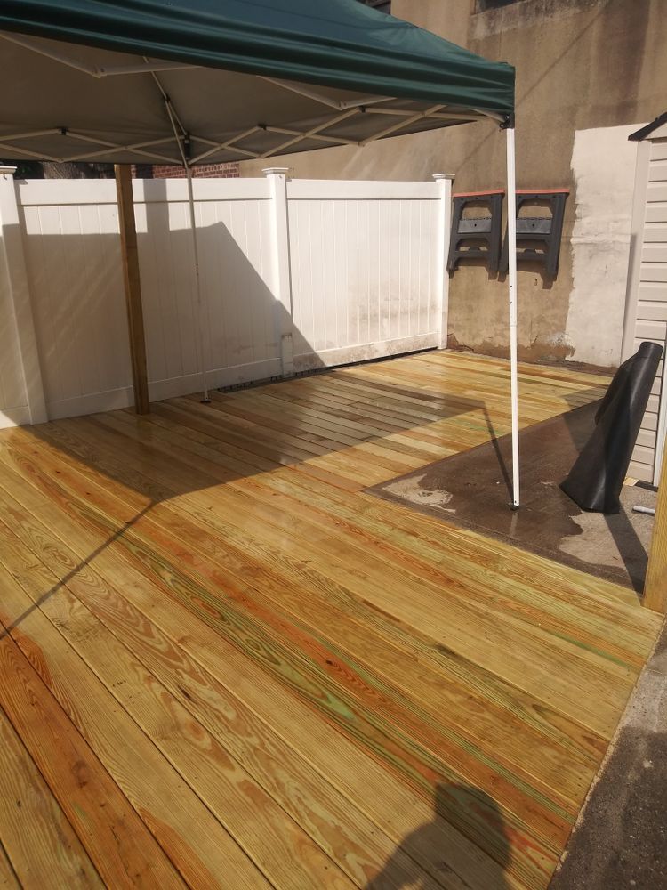 A wooden deck with a canopy and a white fence in the background