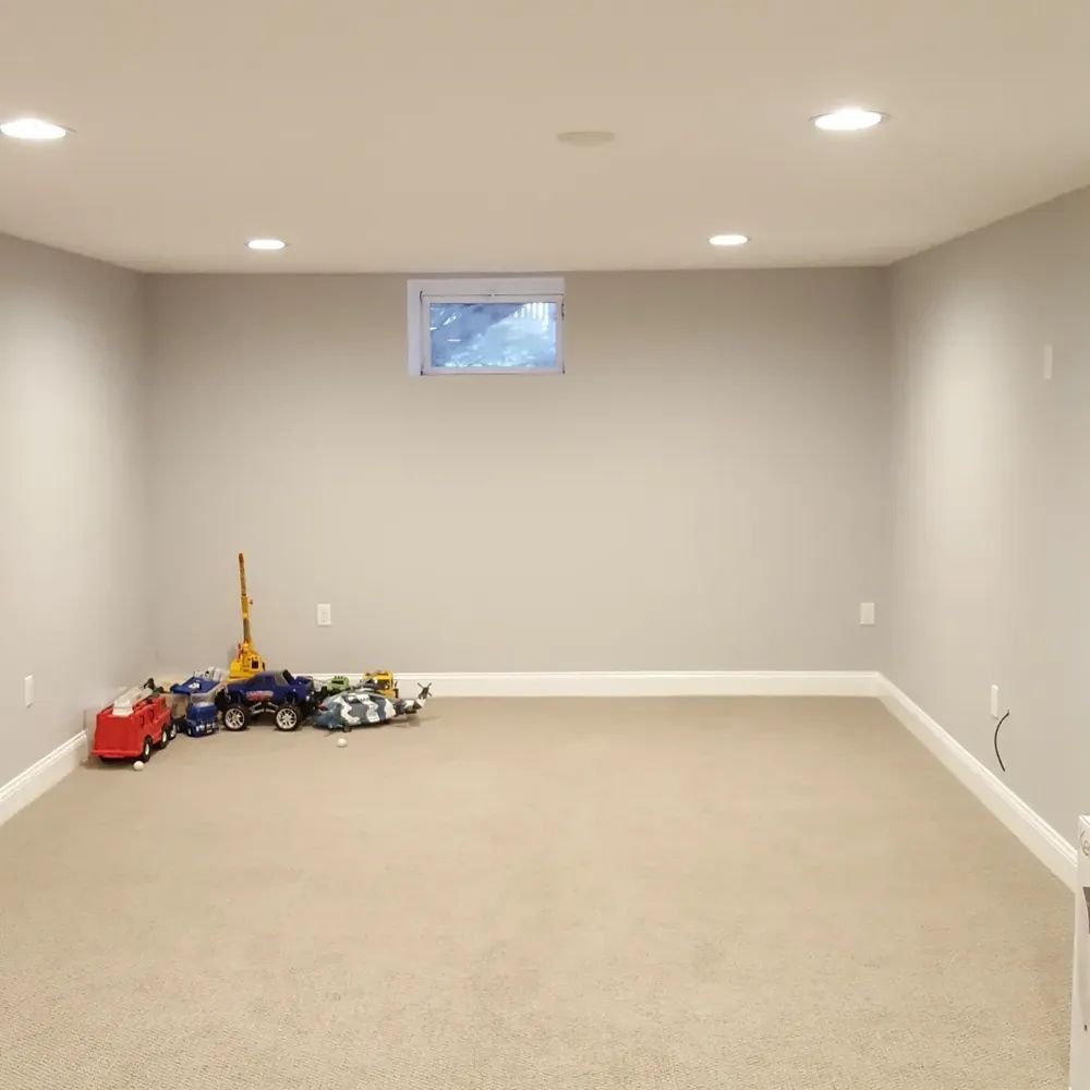 An empty basement with a window and toys on the floor
