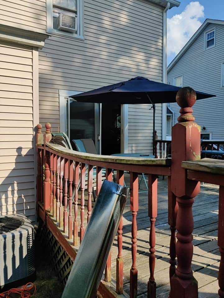 A deck with a slide and umbrella in front of a house