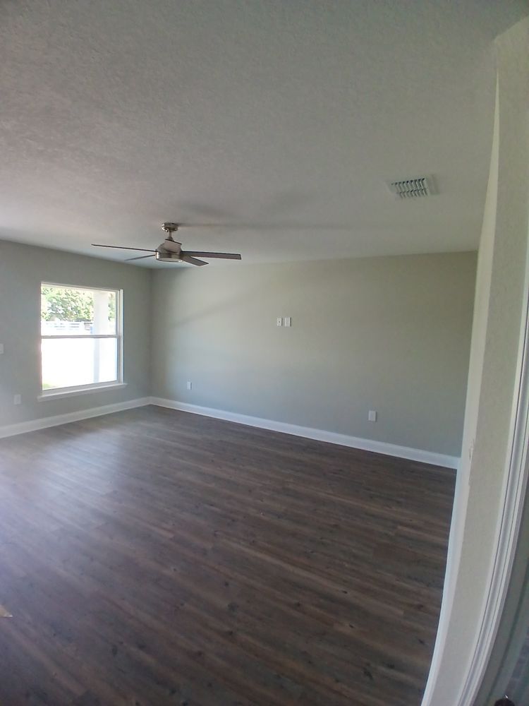 An empty living room with hardwood floors and a ceiling fan.