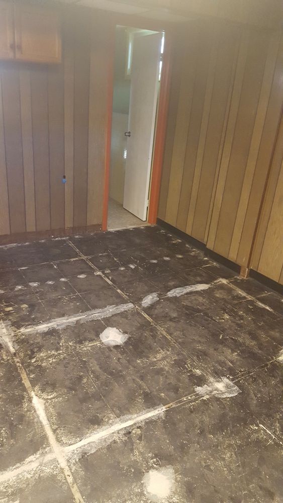 A room with a dirty floor and wooden walls