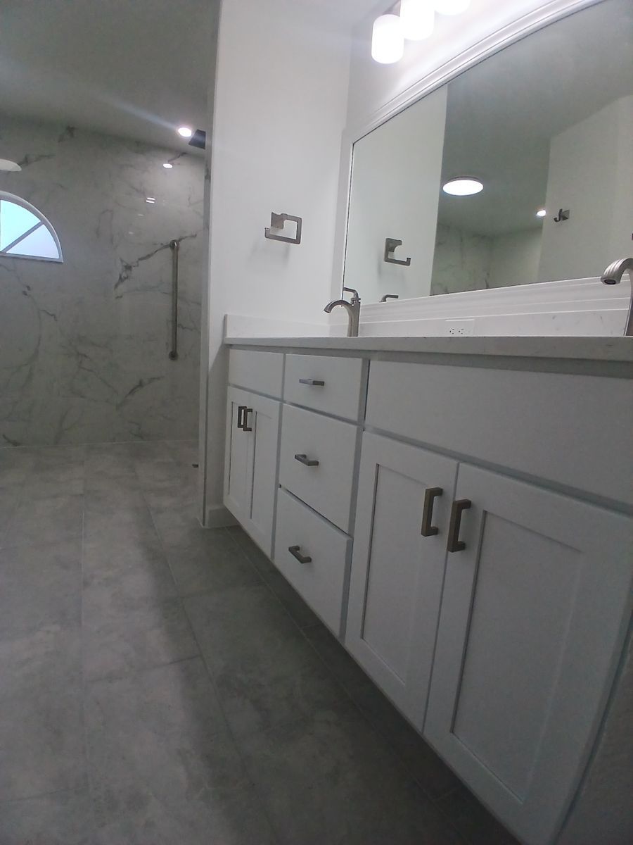 A bathroom with two sinks , a mirror and a walk in shower