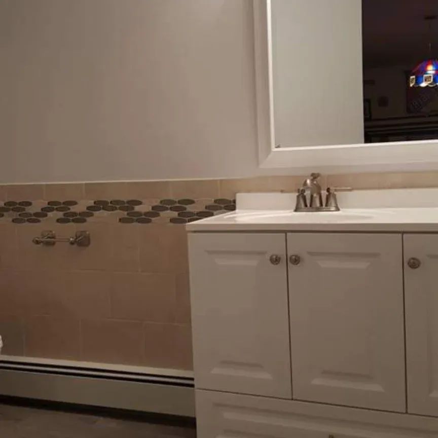 A bathroom with a sink, mirror, and cabinets