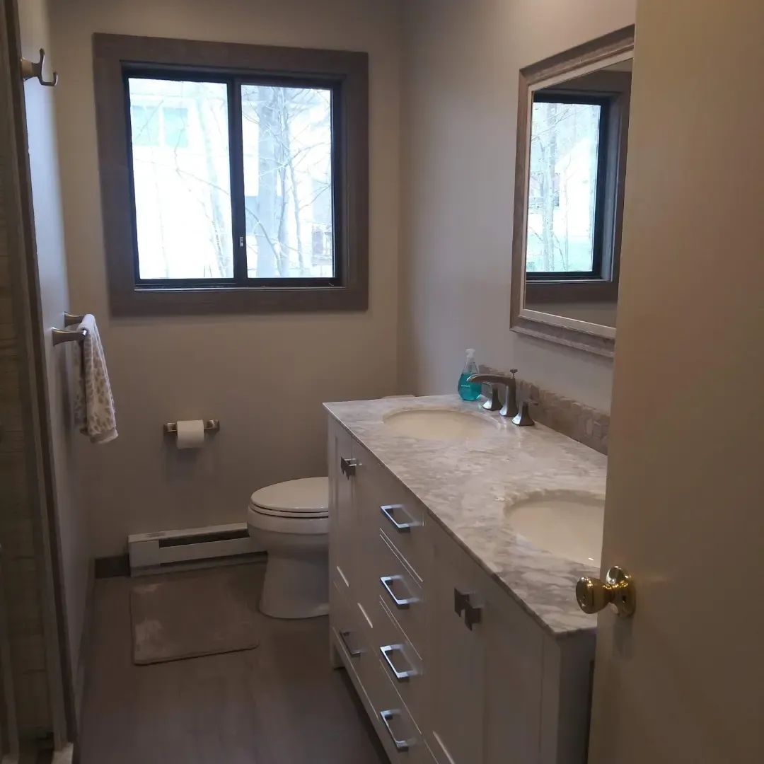A bathroom with two sinks, a toilet, and a mirror