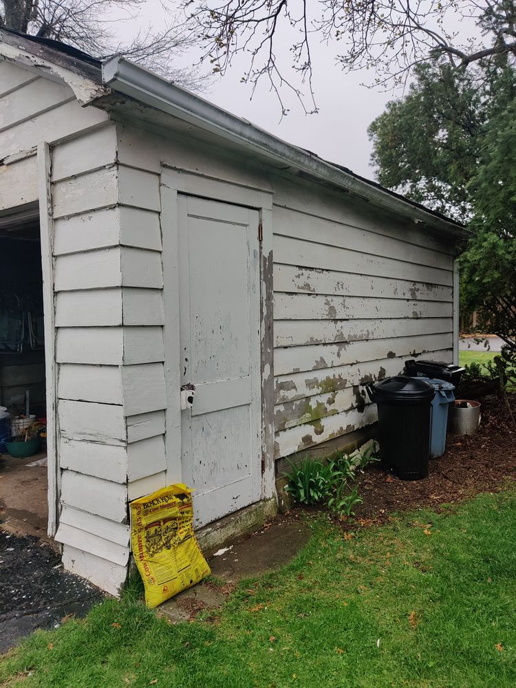 A white shed with a yellow bag on the ground in front of it