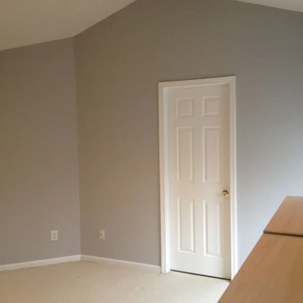 An empty room with gray walls and a white door