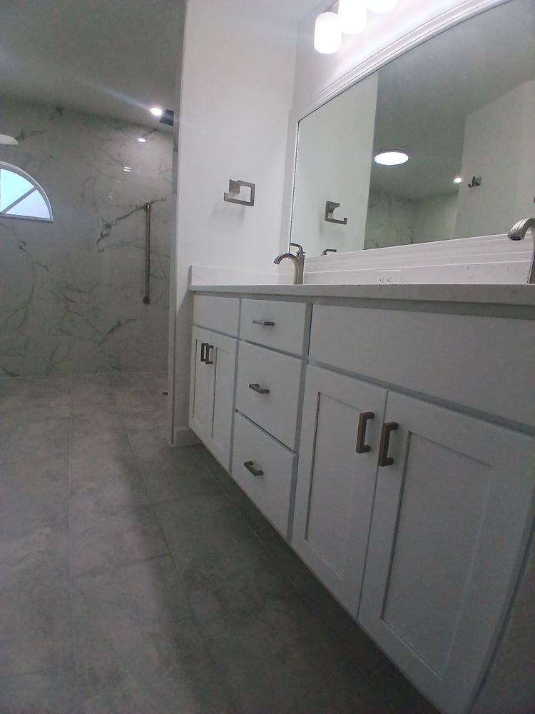 A bathroom with two sinks, a mirror and a walk in shower